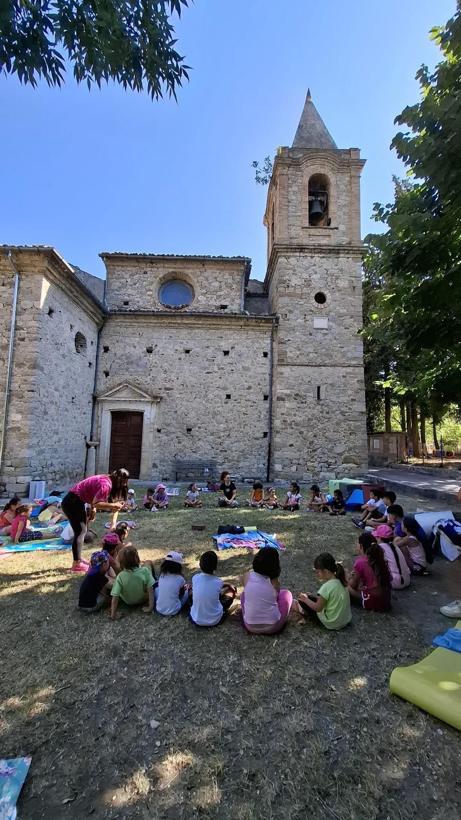 Bambini seduti all'aperto durante un'attività della scuola